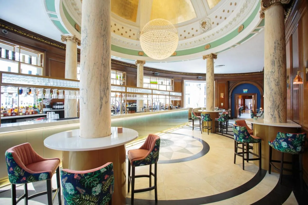 a lobby of a hotel with a bar and chairs at voco Grand Central Glasgow by IHG in Glasgow