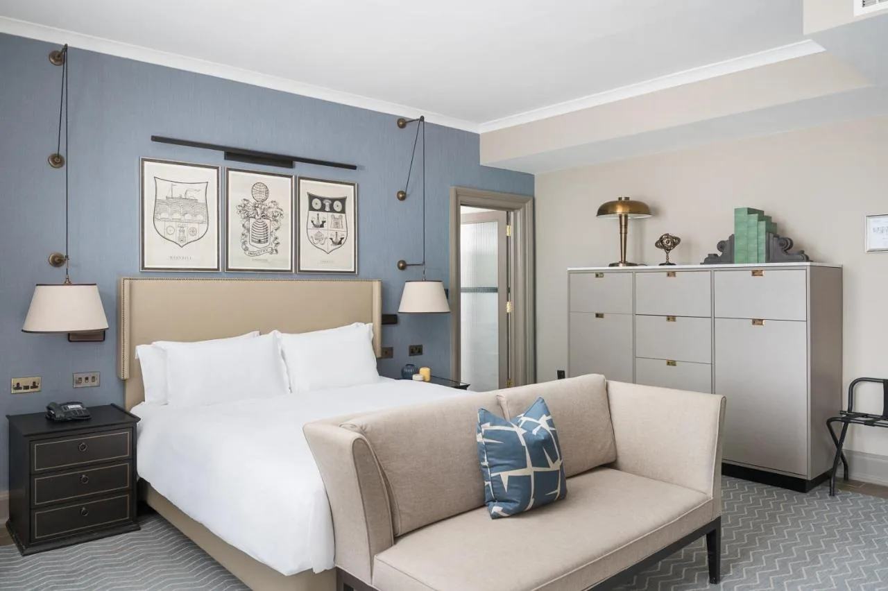 a bedroom with a large bed and a chair at voco Grand Central Glasgow by IHG in Glasgow