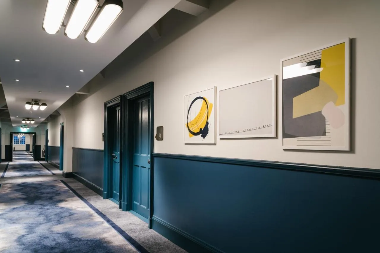 a hallway with blue doors and paintings on the wall at voco Grand Central Glasgow by IHG in Glasgow