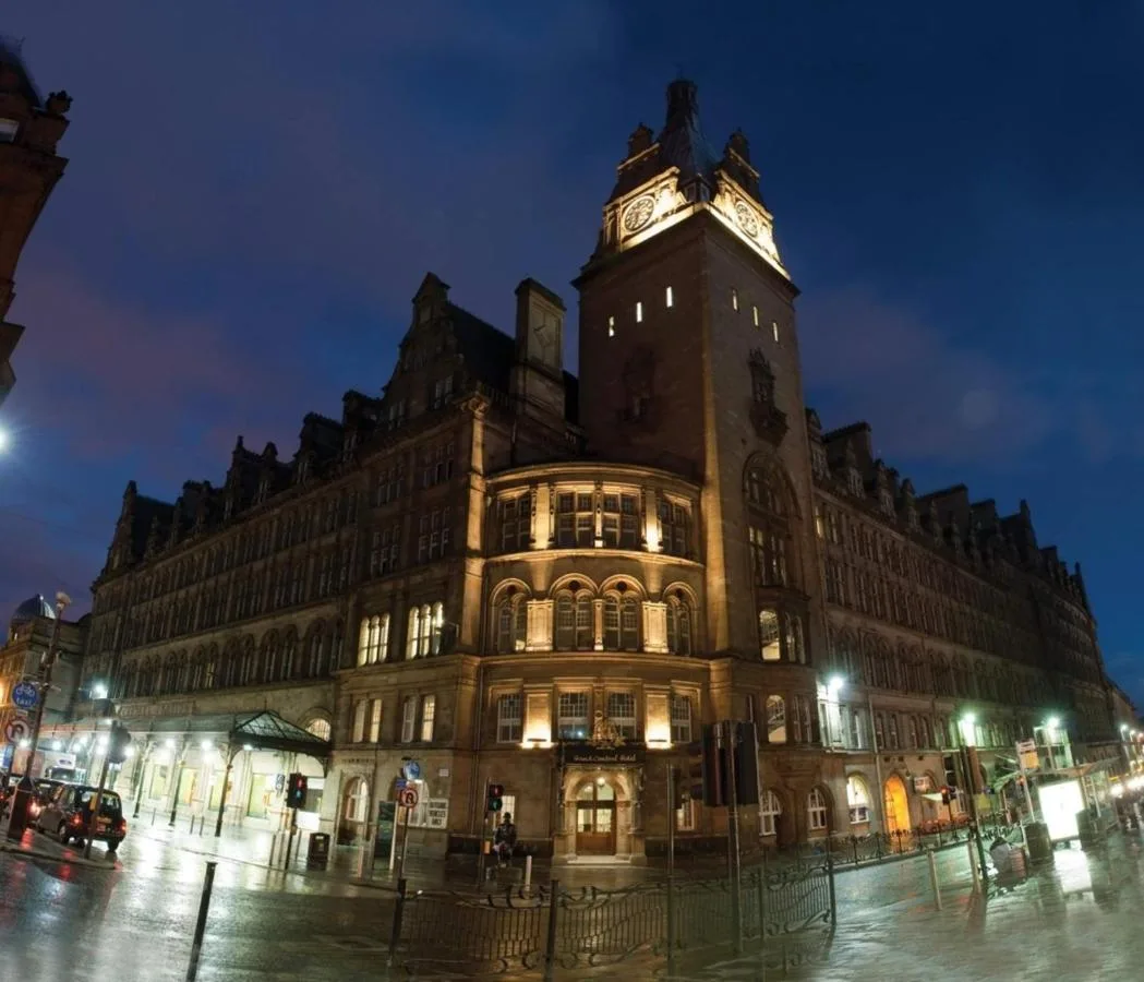 a large building with a clock tower at night at voco Grand Central Glasgow by IHG in Glasgow
